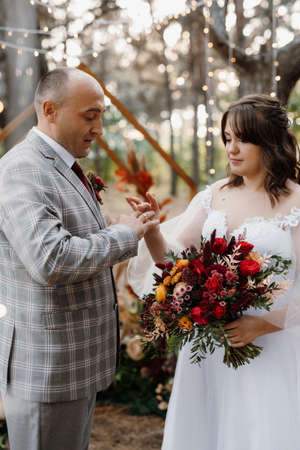 man and woman got engaged in autumn forest at wedding decorated ceremonyの写真素材