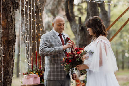 man and woman got engaged in autumn forest at wedding decorated ceremonyの写真素材