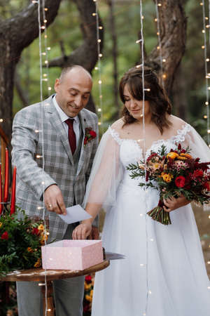 man and woman got engaged in autumn forest at wedding decorated ceremonyの写真素材