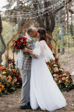 man and woman got engaged in autumn forest at wedding decorated ceremonyの写真素材