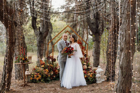 man and woman got engaged in autumn forest at wedding decorated ceremonyの写真素材
