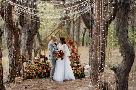 man and woman got engaged in autumn forest at wedding decorated ceremonyの写真素材