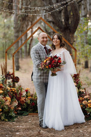 man and woman got engaged in autumn forest at wedding decorated ceremonyの写真素材