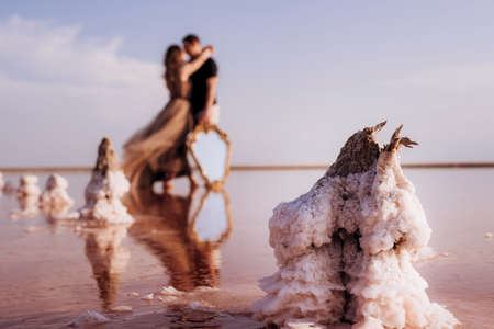 girl and a guy on the shore of a pink salt lake at sunset