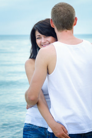 guy and a girl in jeans and white t-shirts on the seashoreの写真素材