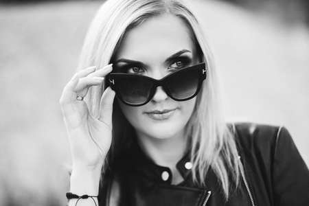 blonde girl in a black trouser suit with blue eyes on the background of a granite quarry from gray rubbleの写真素材