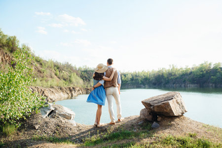 a young couple a guy and a girl are walking near a mountain lake surrounded by granite rocksの写真素材