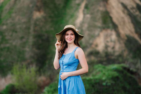 young girl in a straw hat with large brim on mountain green slopesの写真素材