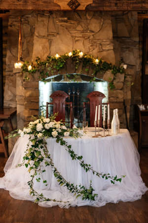 The presidium of the newlyweds in the banquet hall of the restaurant is decorated with candles and green plants, wisteria hangs from the ceilingの写真素材
