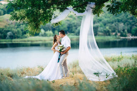 young couple a girl and a guy are walking in the field against the background of the riverの写真素材