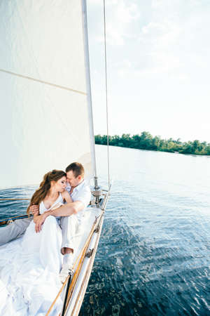 young couple guy and girl on a white sailing yachtの写真素材