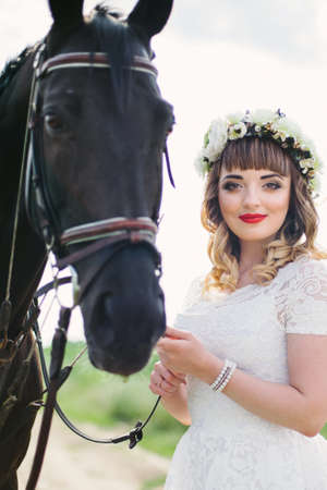 girl with red lips in a white dress near a black horseの写真素材