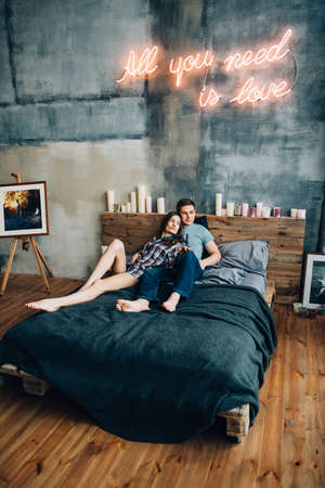 a guy and a girl lie on the bed in the room and look at each otherの写真素材