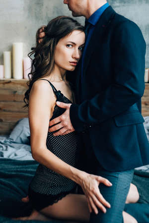 a girl and a guy are standing near the bed in the bedroom next to the windowの写真素材