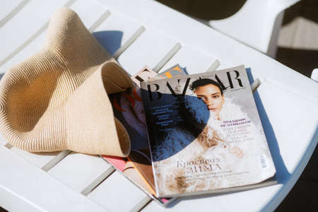 a magazine and a hat on a lounger left by the pool on a hot dayの写真素材