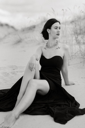girl in a black long dress in a sandy desert under a blue skyの写真素材
