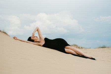 girl in a black long dress in a sandy desert under a blue skyの写真素材