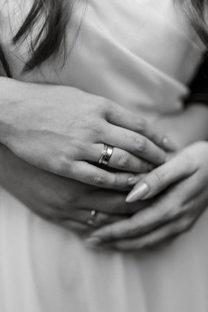 the bride and groom tenderly hold hands between them love and relationshipsの写真素材