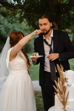 newlyweds happily cut, laugh and taste the wedding cakeの写真素材
