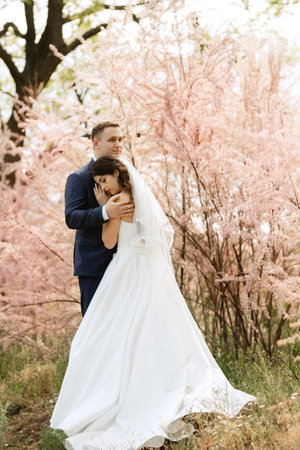 the groom and the bride are walking in the forest on a bright dayの写真素材