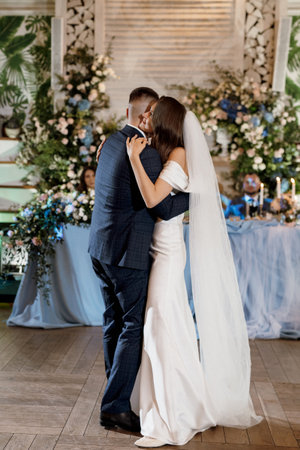 the first wedding dance of the bride and groom inside the restaurant hall in sunset lightの写真素材