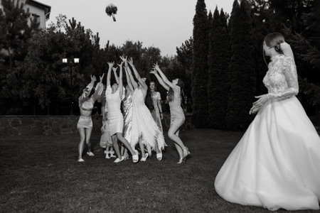 a bride in a white dress throws a wedding bouquet to her unmarried girlfriendsの写真素材