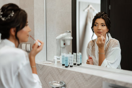 bride in a veil with makeup paints her lips in the bathroomの写真素材