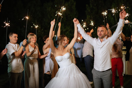 newlyweds at a wedding in the corridor of sparklersの写真素材