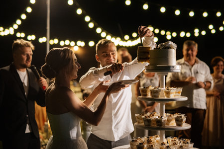 newlyweds happily cut, laugh and taste the wedding cakeの写真素材