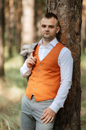portrait of the groom in a gray suit and an orange vest and white sneakersの写真素材