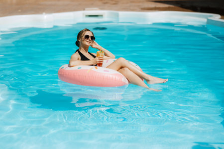 a girl in a black swimsuit floats on an inflatable circle in a blue pool