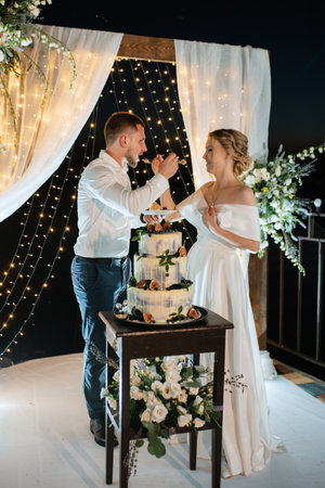 newlyweds happily cut, laugh and taste the wedding cake