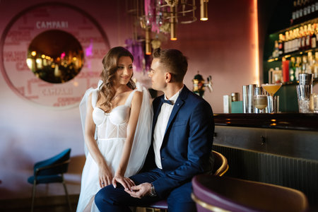 bride and groom inside a cocktail bar in a bright atmosphere with a glass of drinkの写真素材