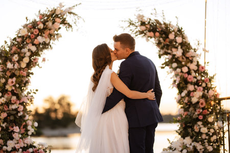 bride and groom against the backdrop of a yellow sunset on a pier near the river