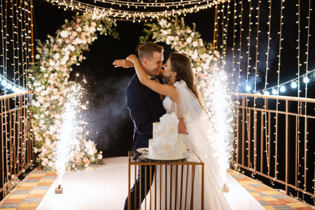 newlyweds happily cut, laugh and taste the wedding cakeの写真素材