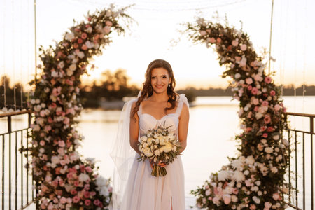 bride against the background of a yellow sunset on a pier near the riverの写真素材