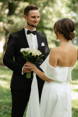 the first meeting of the bride and groom in wedding outfits in the parkの写真素材
