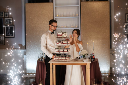 newlyweds happily cut, laugh and taste the wedding cakeの写真素材