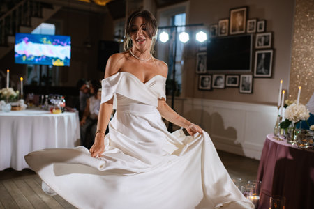 bride in a white dress dances emotionally at an evening banquetの写真素材