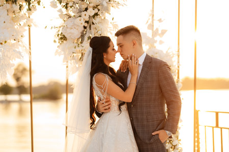 bride and groom against the backdrop of a yellow sunset on a pier near the riverの写真素材