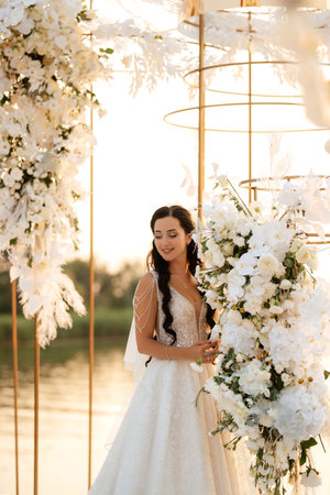 bride against the background of a yellow sunset on a pier near the riverの写真素材