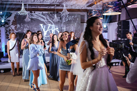 bride in a white dress throws a wedding bouquet to her unmarried girlfriendsの写真素材