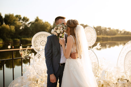 bride and groom against the backdrop of a yellow sunset on a pier near the riverの写真素材