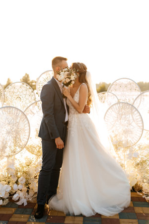 bride and groom against the backdrop of a yellow sunset on a pier near the riverの写真素材