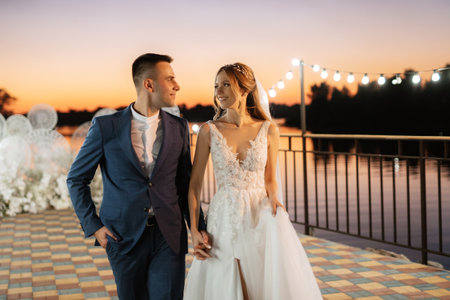 bride and groom against the backdrop of a yellow sunset on a pier near the riverの写真素材