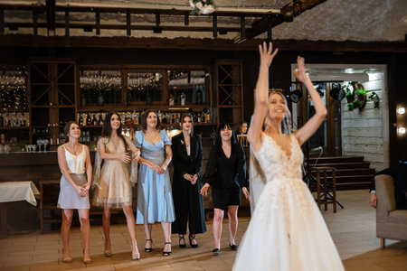 bride in a white dress throws a wedding bouquet to her unmarried girlfriendsの写真素材