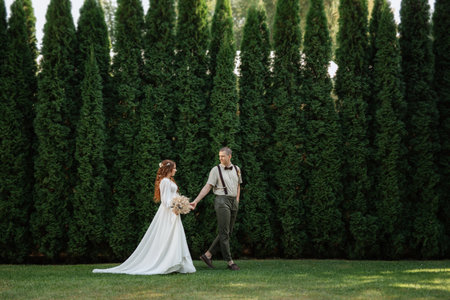 wedding walk of the bride and groom in a coniferous park in summerの写真素材