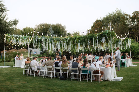 evening wedding family dinner in the forest with light bulbs and candlesの写真素材