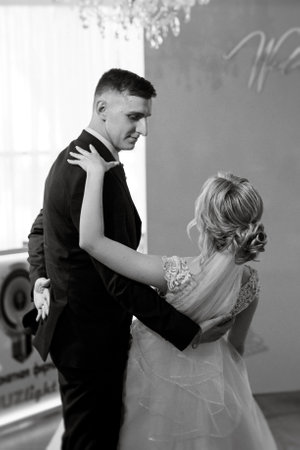the first wedding dance of the bride and groom inside the restaurant hall in sunset lightの写真素材