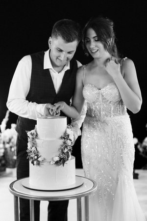 newlyweds happily cut, laugh and taste the wedding cakeの写真素材